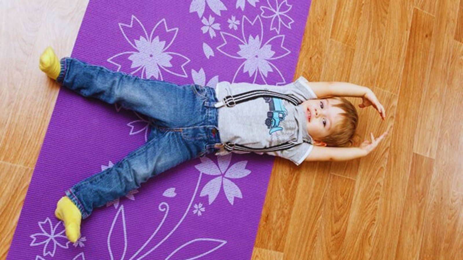 A young child resting on a purple yoga mat, enjoying a moment of relaxation and calmness.