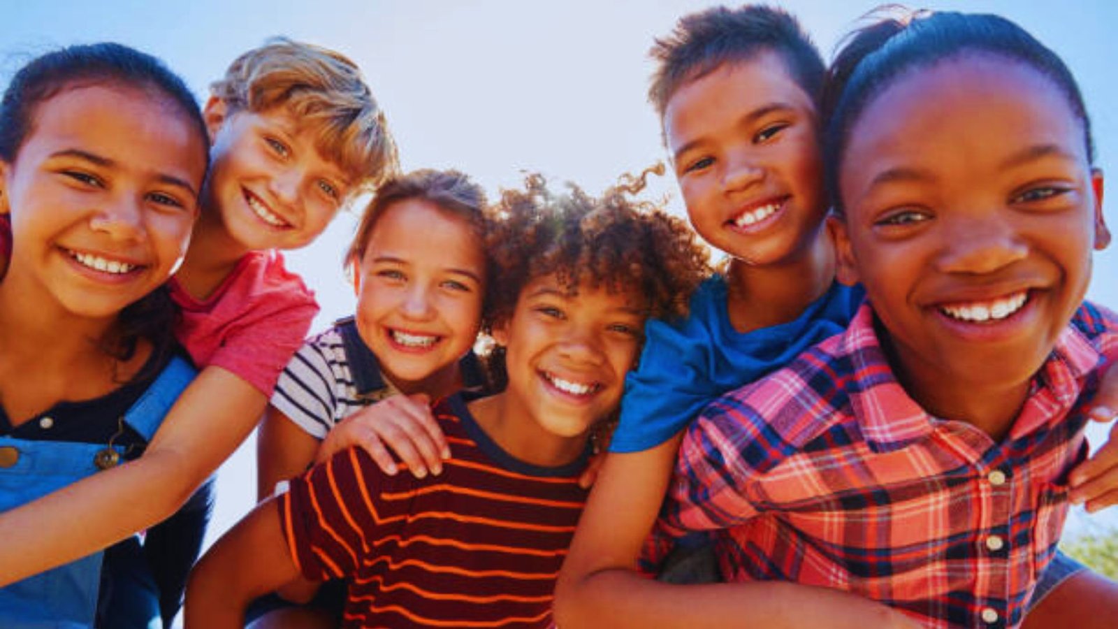 A group of smiling children poses together for the camera, showcasing their joy and camaraderie.
