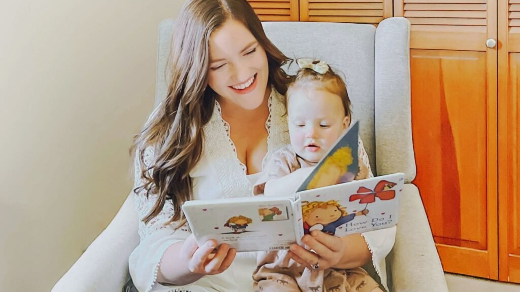 A woman reads to her b aby in a chair, illustrating the importance of bonding during the 2 to 1 nap transition.