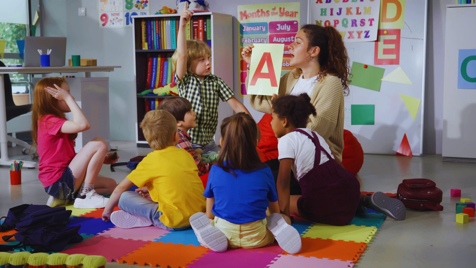  A group of children sitting on the classroom floor, engaged in activities, with a daily schedule visible nearby.
