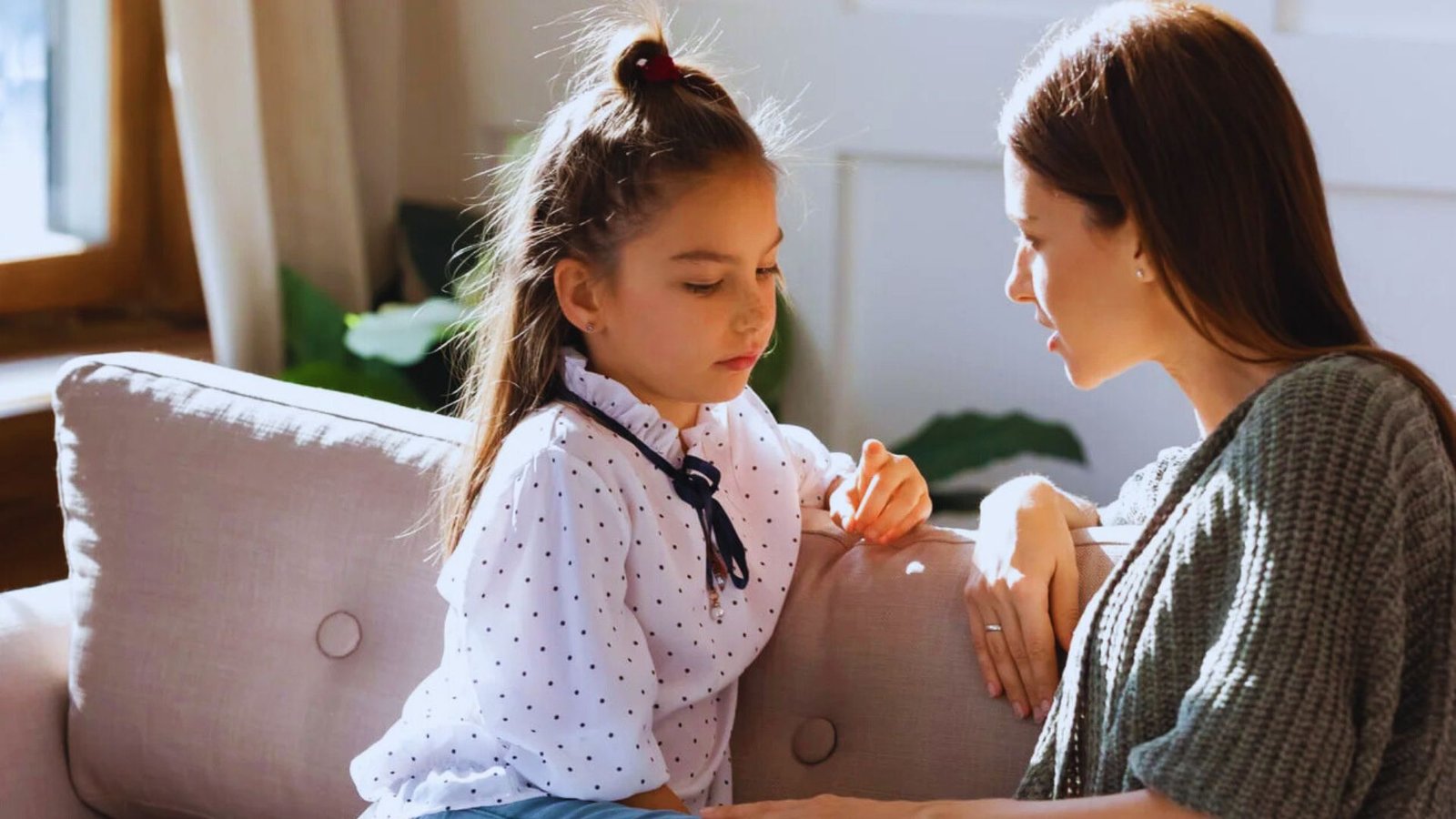  A woman and a young girl sit together on a couch, sharing a moment of comfort and companionship.