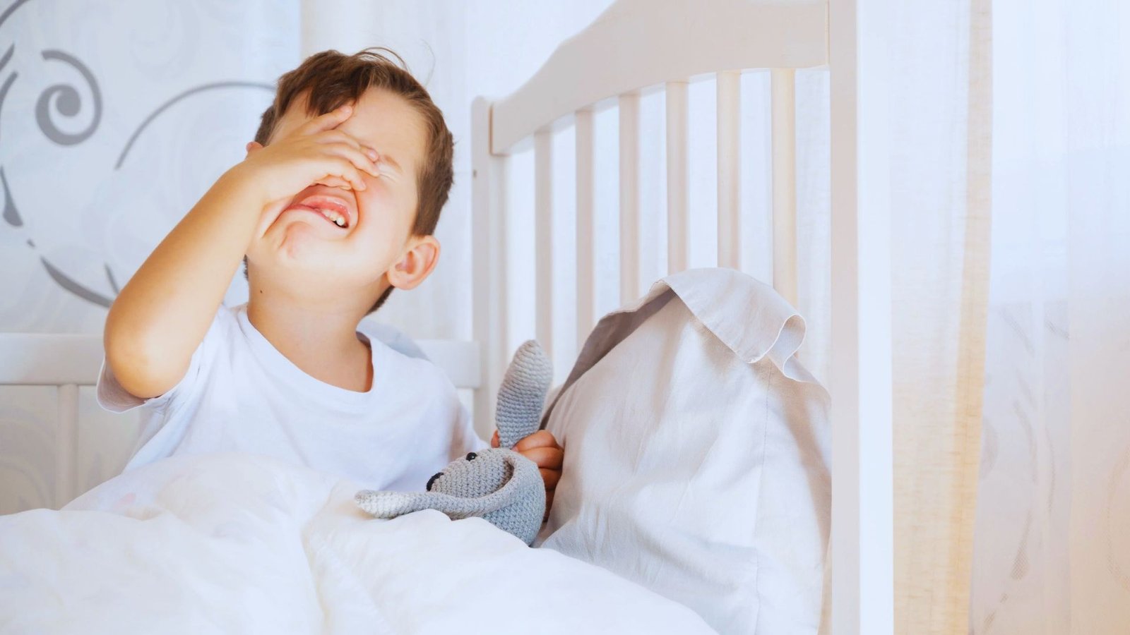 A young boy stressed in his bed, highlighting the stalling struggle of bedtime routines.
