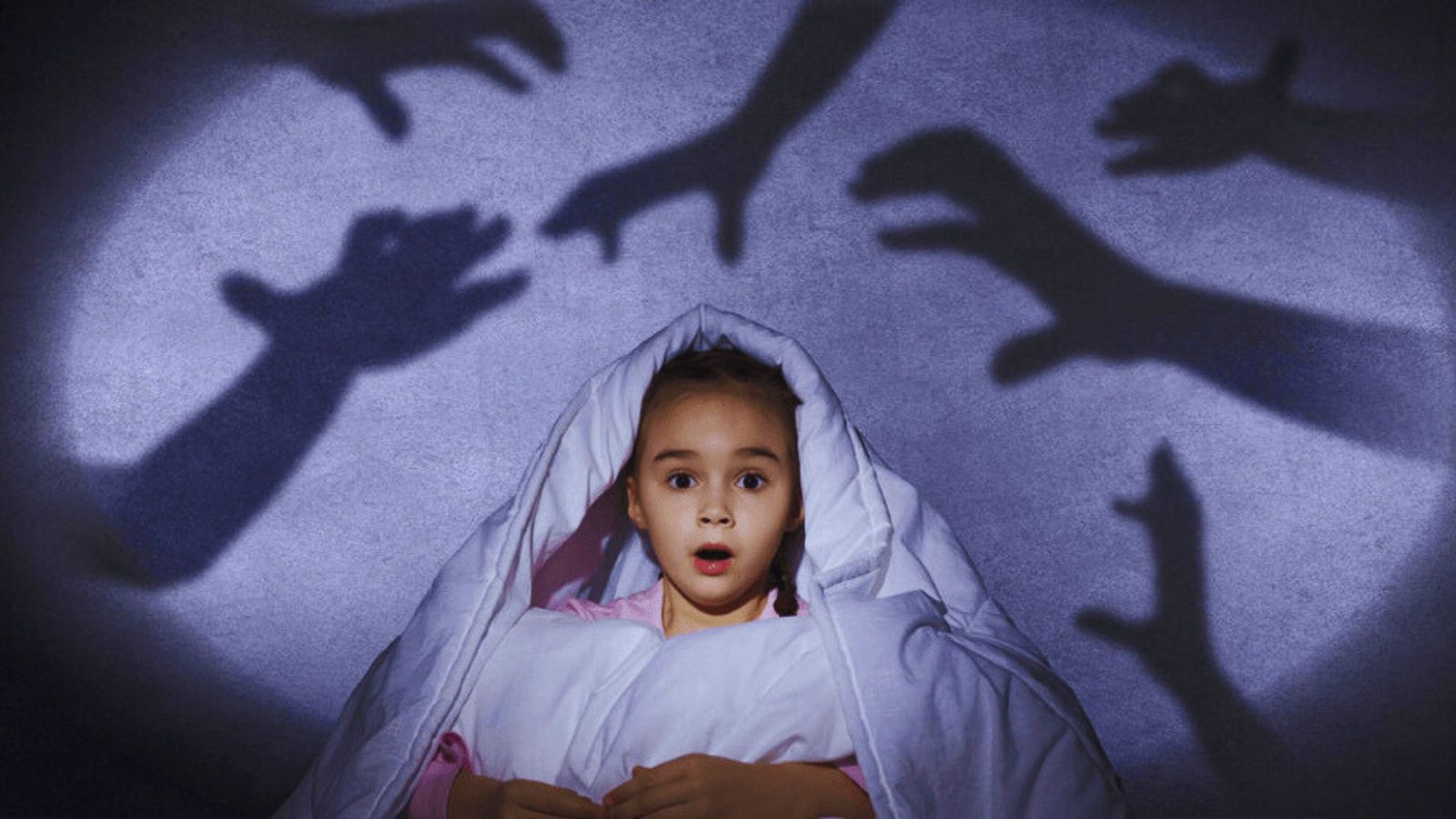 A young girl wrapped in a blanket reaches out with her hands, expressing fear or seeking comfort in the dark.

