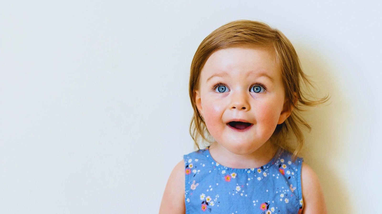  A baby girl with blue eyes gazes up at the camera, capturing a moment of innocence and curiosity.
